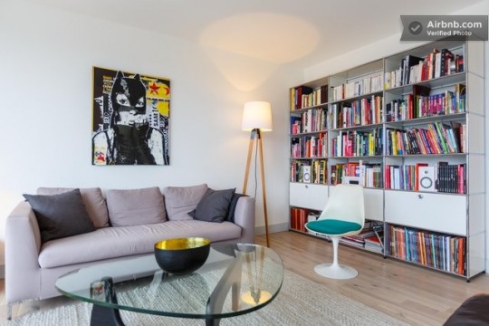 Salon avec un canapé gris, un tableau BD et une grande bibliothèque